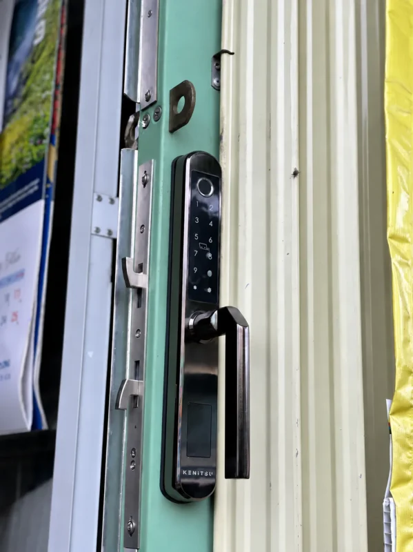 Mặt ngoài Kenitsu SX9 và phần thân khóa trên đố cửa nhôm màu sáng